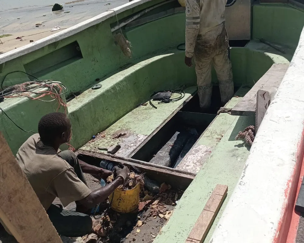 Men repairing a green fishing boat at the waterfront