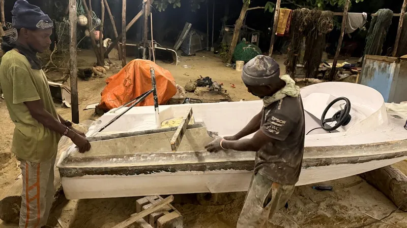 Two young men building a fibreglass boat at night